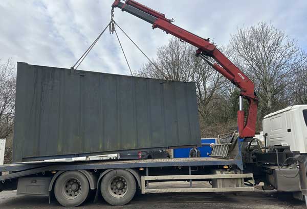Hiab crane lifting a huge container onto low loader