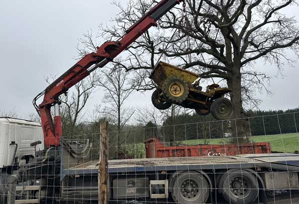 Hiab crane lifting a digger from field onto back of low loader