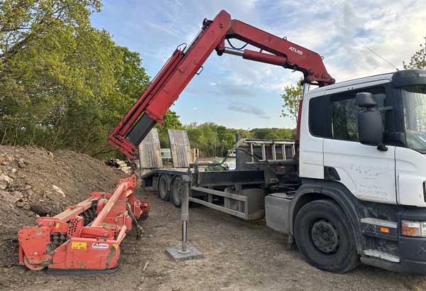 Hiab crane being used to lift a heavy machinery for transportation